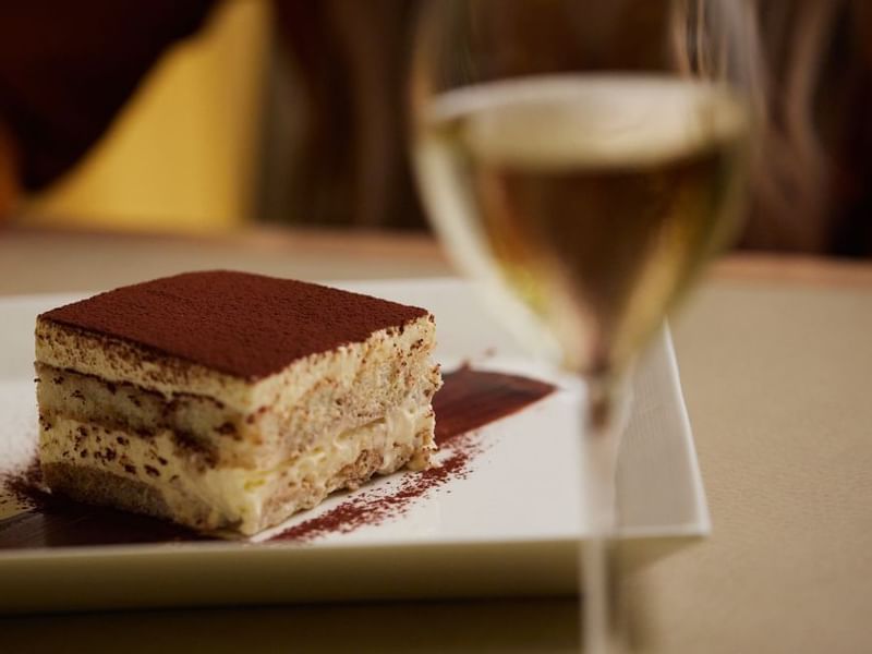 Slice of cake on a plate with a glass of wine in Modo Mio at Crown Promenade Perth