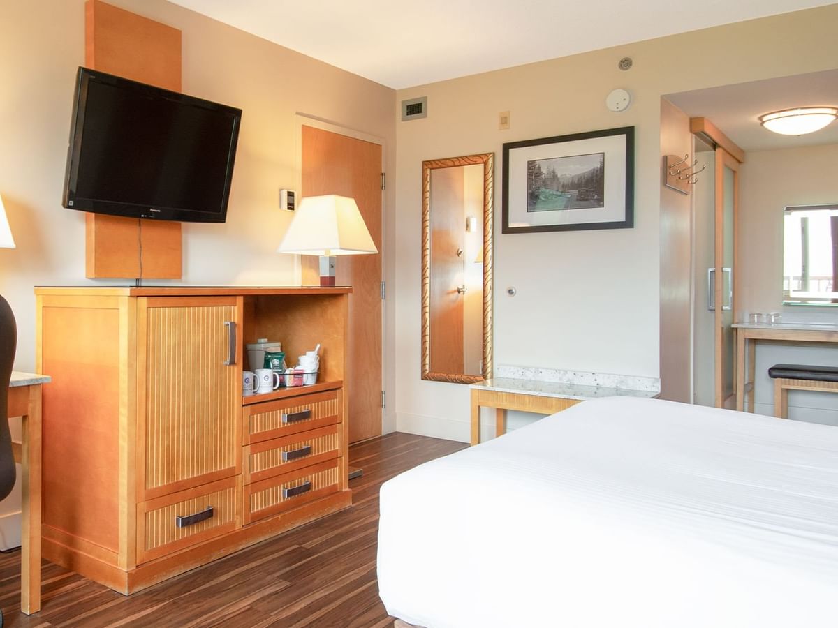 Hotel guest room with a queen bed, TV, and work desk