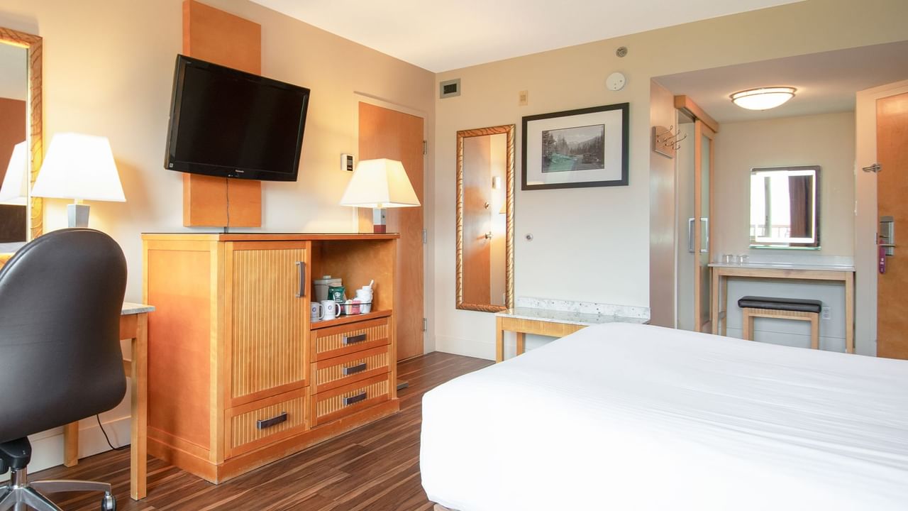 Hotel guest room with a queen bed, TV, and work desk