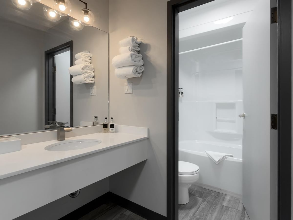 Modern bathroom with floating vanity, black-framed mirror and separate toilet area.