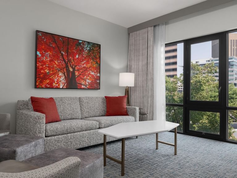 Parlor Suite living room with a gray patterned couch, a large window, and an abstract red tree art piece at Hotel 43 Boise