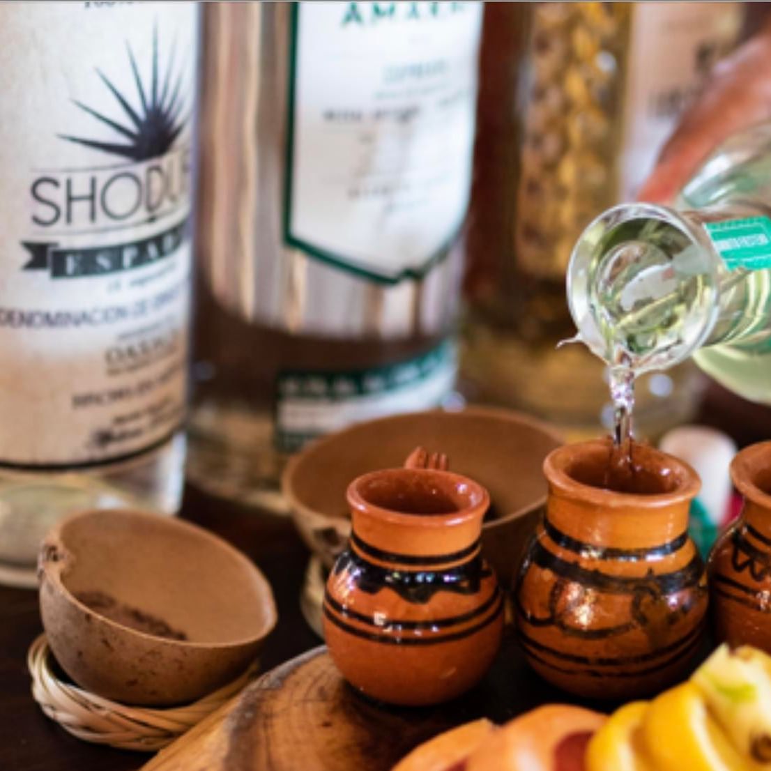 La Zebra Hotel guest enjoying a tasting experience with various artisanal mezcal bottles and traditional clay copitas