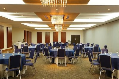A large banquet room at Hotel Mykonos with multiple tables set for an event with blue linens