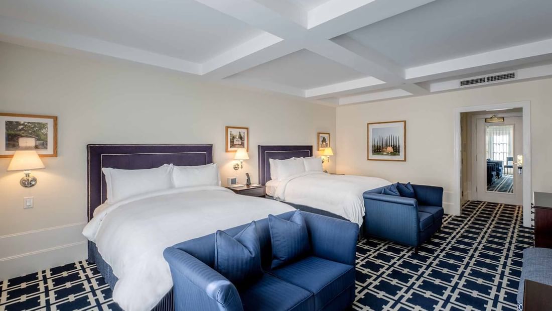 Cozy sofas and nightstands by the beds in Deluxe Queen Queen Room with geometric patterned carpet at El Prado Hotel