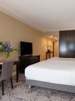 Twin beds by a dark wooden desk under gold mirrors in Family room with two queen beds at Warwick Paris Champs Elysées