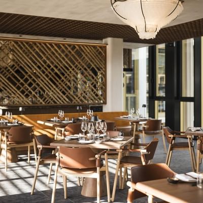 Interno di un ristorante elegante con tavoli e sedie, vetrate e luce naturale.