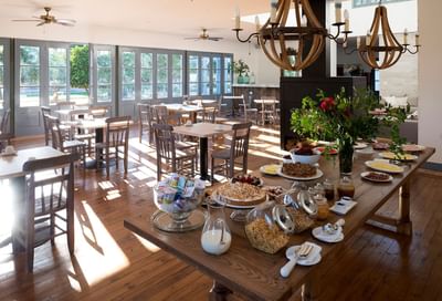 Pastries on a wooden table by cereal jars under globe chandeliers in the Ensamblaje Restaurant at NOI Blend Colchagua