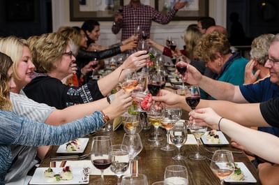Group of people in a long table toasting wine and enjoying snacks at The Stanley Hotel