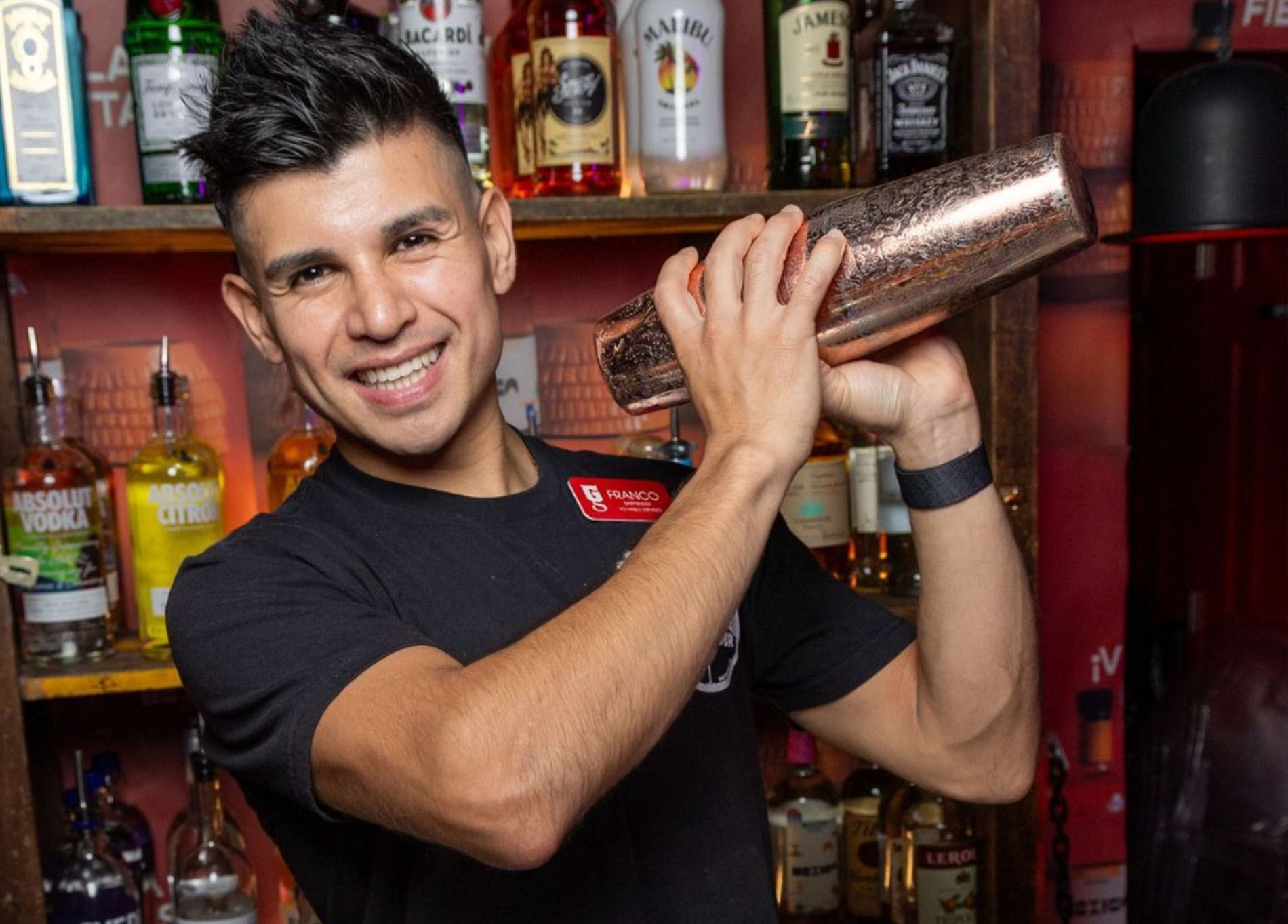 a man holding a shaker in front of a bar
