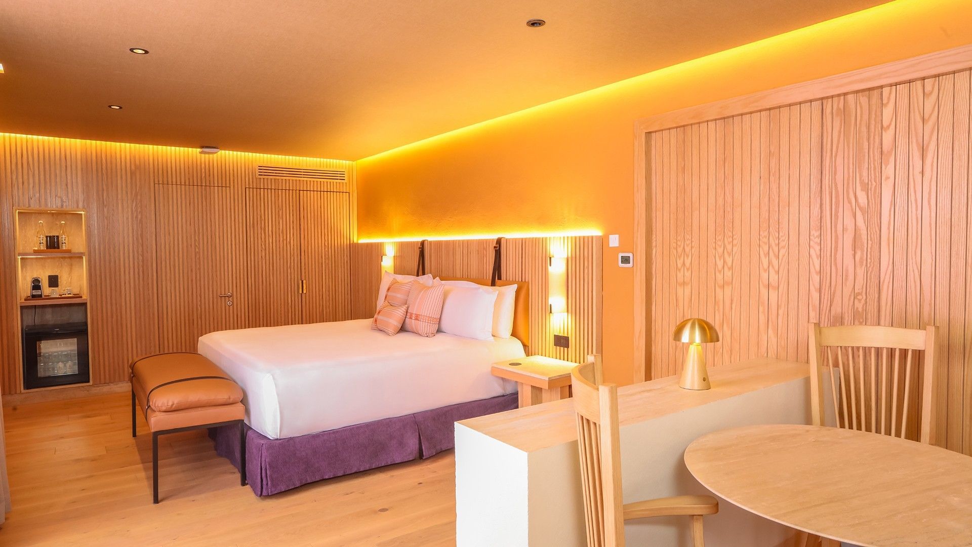 King Superior Junior Suite with an orange glow, wooden accents, and a small dining table at Camino Real Polanco Mexico
