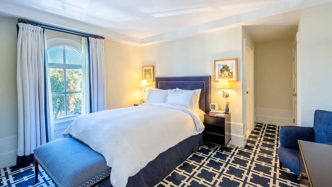 Comfortable hotel room at El Prado Hotel, featuring a large bed, elegant decor, and a window with a view