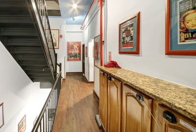 Chelsea Pines Inn NYC hallway with wooden floors, staircase, vintage posters, red telephone, and granite counter