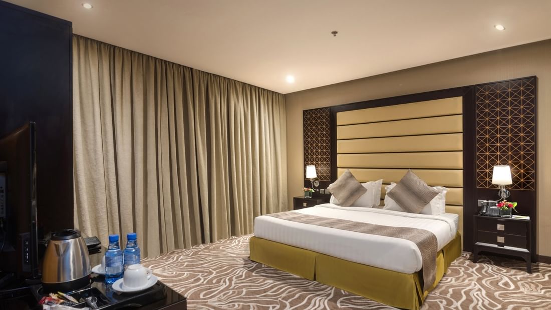 Standard King / Twin Bed features King-sized bed by a dark wood nightstand at Naviti by Warwick Al Khobar
