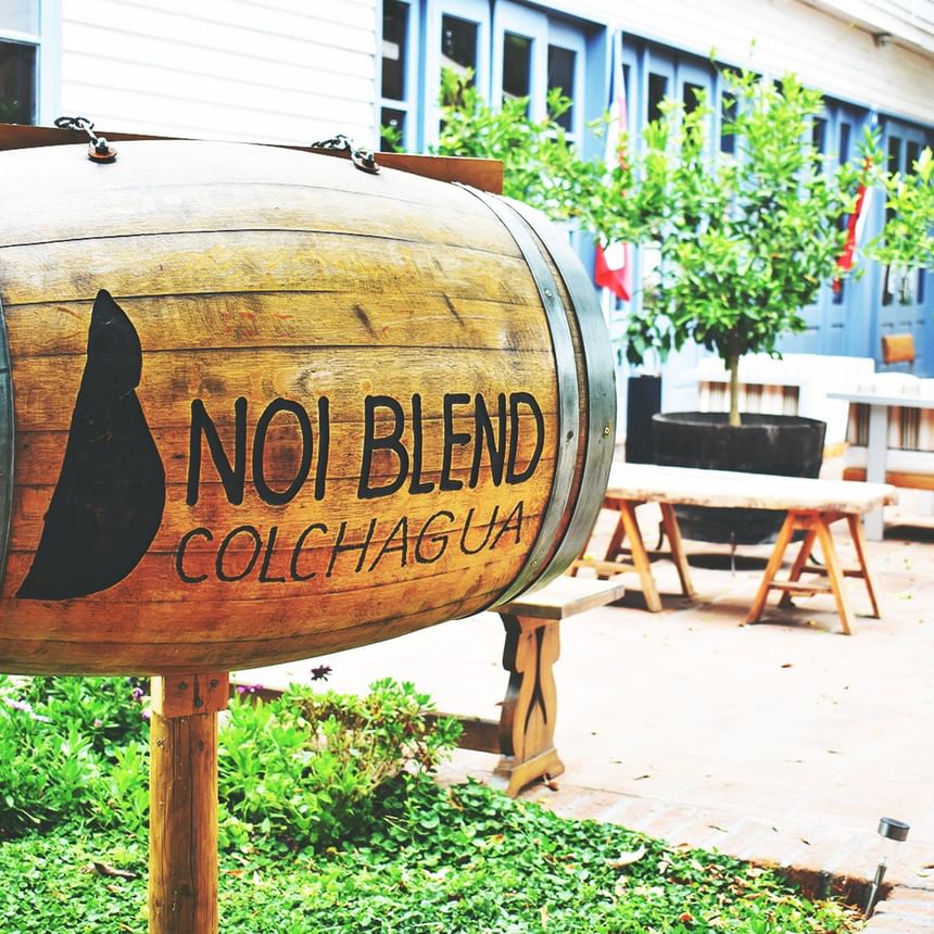 Wooden wine barrel with hotel name by benches and trees at NOI Blend Colchagua, hotels in Colchagua, Valley, Chile