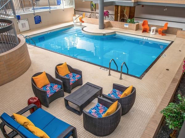 Indoor pool with hot tub and colorful lounge seating at Coast Calgary University Area Hotel by APA in Calgary.