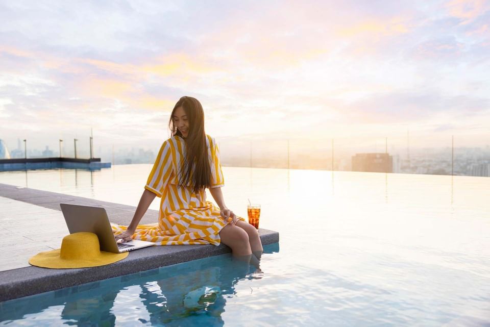 A girl at the edge of a pool with her laptop, Momentus Hotel