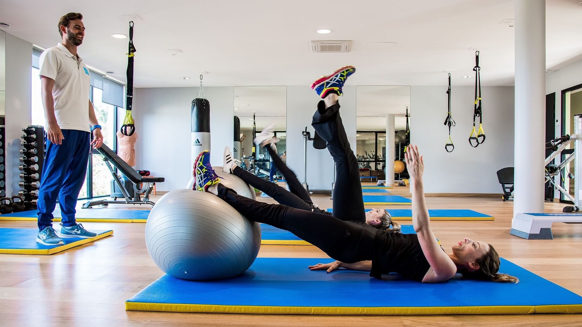 A woman trained by a coach in the gym at The Originals Hotels