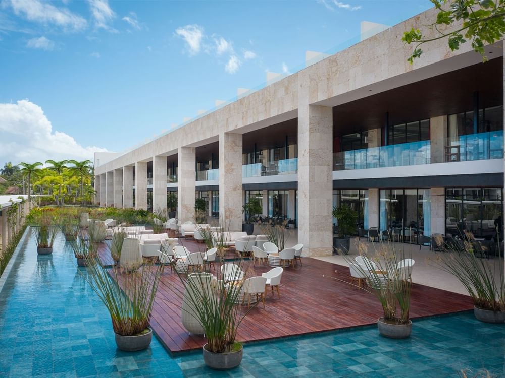 Loungers on wooden deck by a water pool area in front of hotel building at Live Aqua Resorts and Residence Club