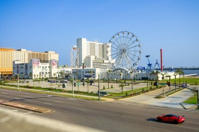 Exterior view of the Margaritaville Resort Biloxi and large Ferris wheel in rooftop water park under a blue sky
