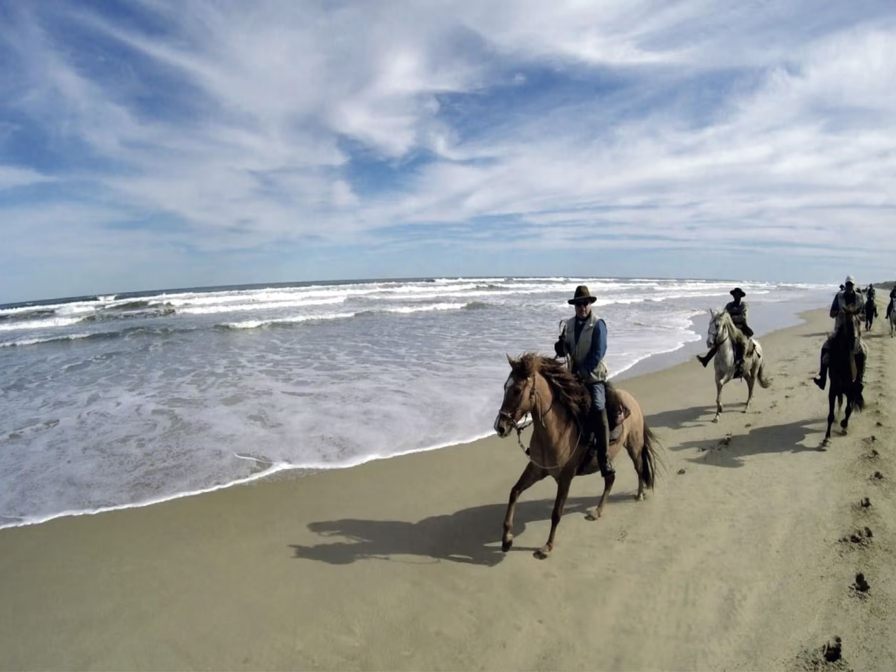 Group of people on horseback riding at the beach near Las Olas Beach Resort