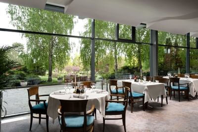 Restaurant Blue Dolphin interior with tables set for dining, featuring large glass windows at Ana Hotels Europa Eforie Nord