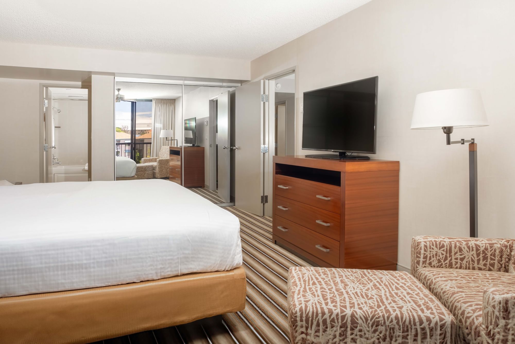 A hotel room with a bed, dresser, chair, and TV.