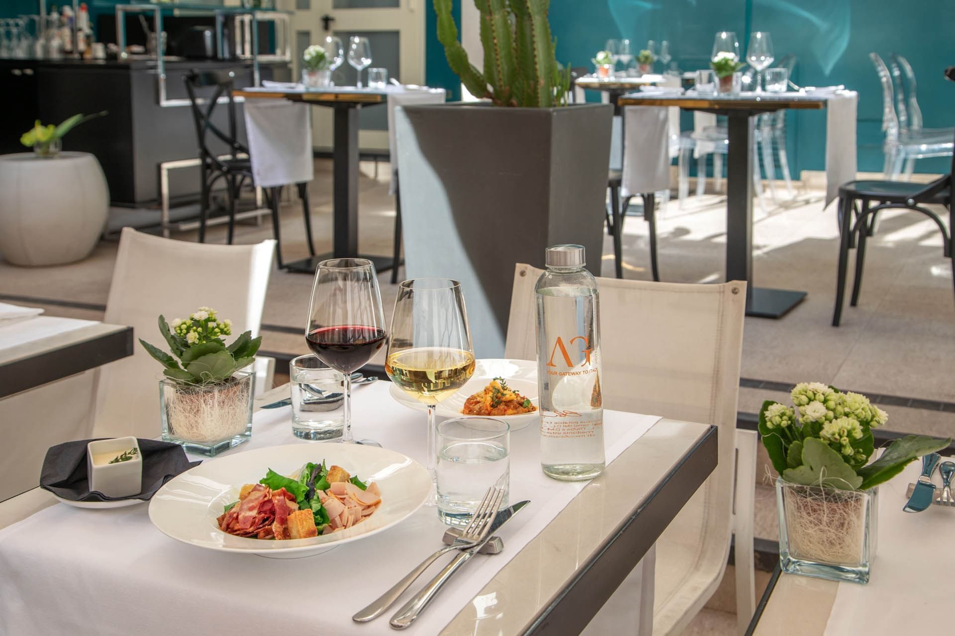 The Guardian Dehors elegant dining table at The Guardian Hotel with a fresh salad, wine glasses, and a water bottle