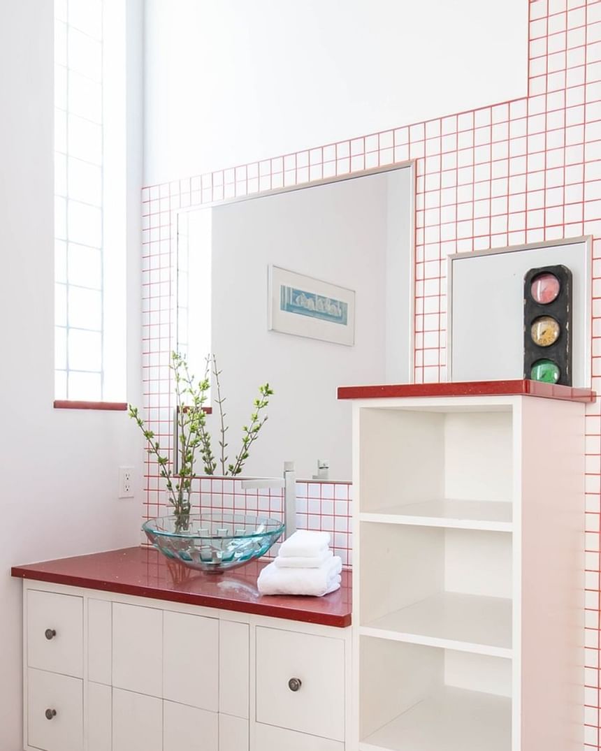 bathroom with red countertop and glass bowl sink 