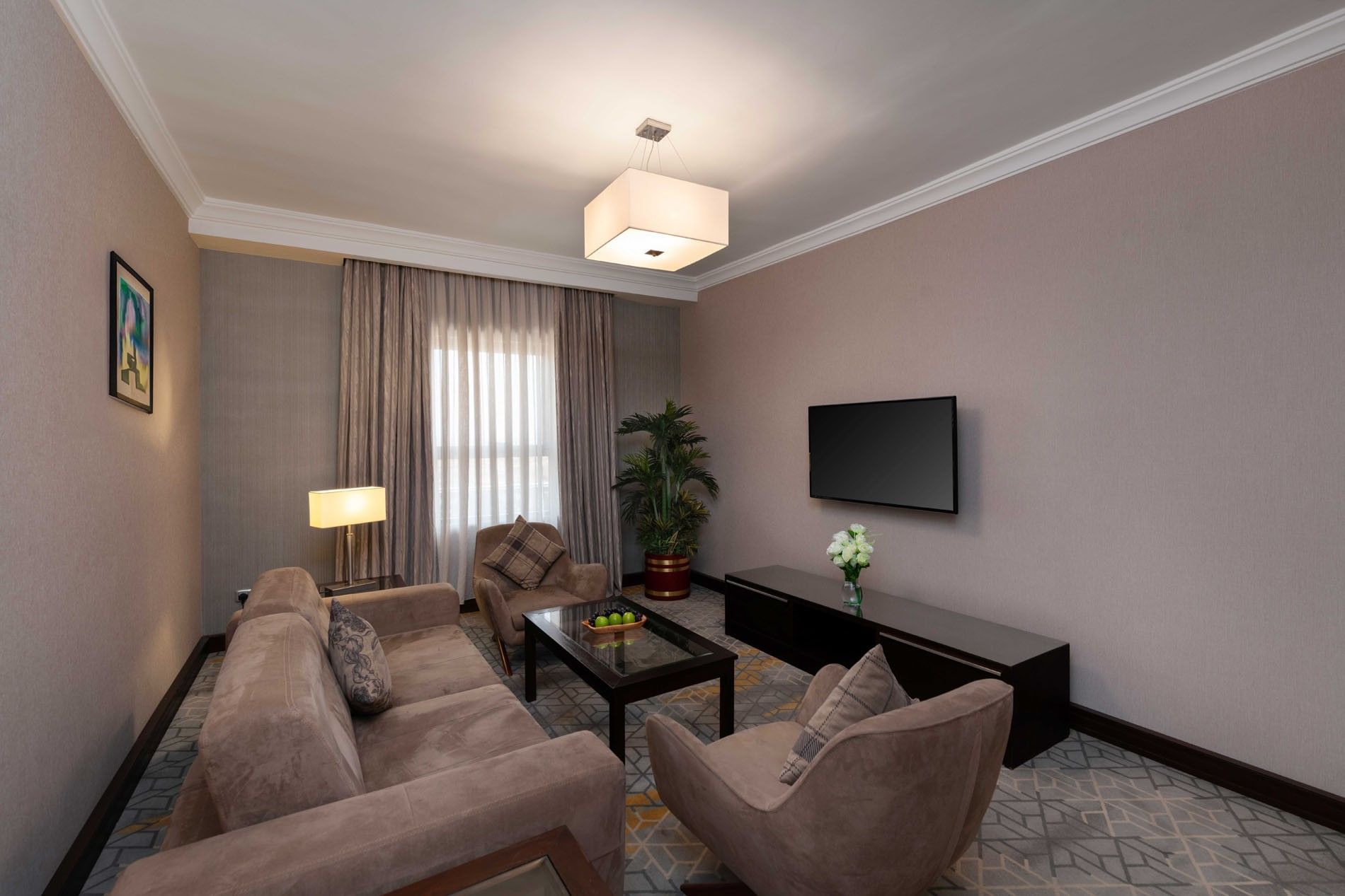 TV lounge area with plush seating and carpeted floors in Executive One-Bedroom Suite at Warwick Hotel Jeddah