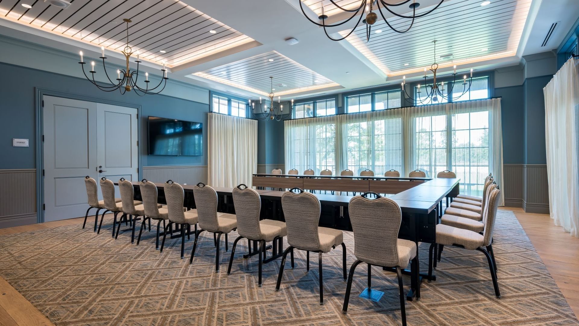 Club Room with elegant chandeliers, long conference table, upholstered chairs, and natural light at Camp Creek Inn.