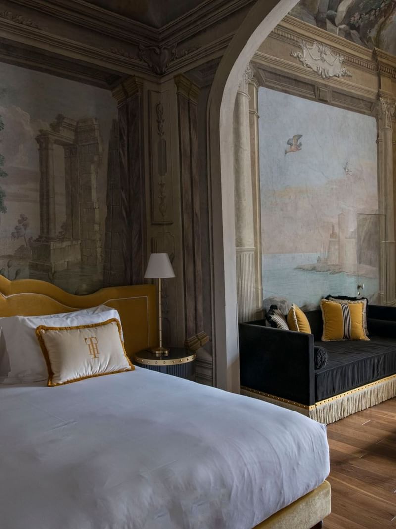 Elegant IL Tornabuoni Hotel room with a plush bed, vintage murals, a couch, and modern decor near AG Hotels