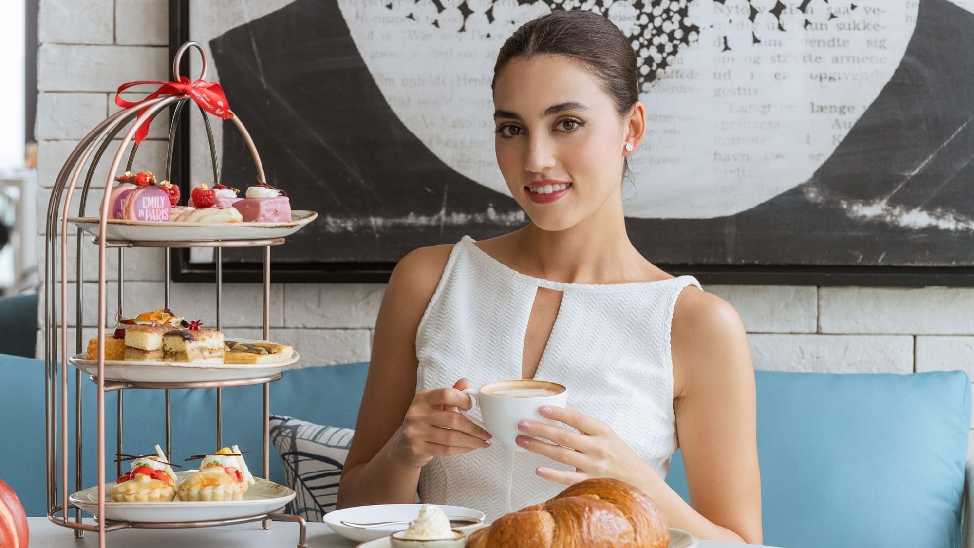 Elegant woman enjoying afternoon tea with pastries and a cappuccino at Paramount Hotel Midtown
