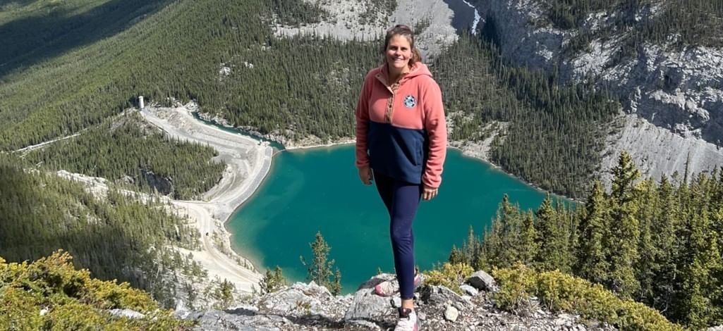 A person poses on the edge of a mountain hike outside of Canmore