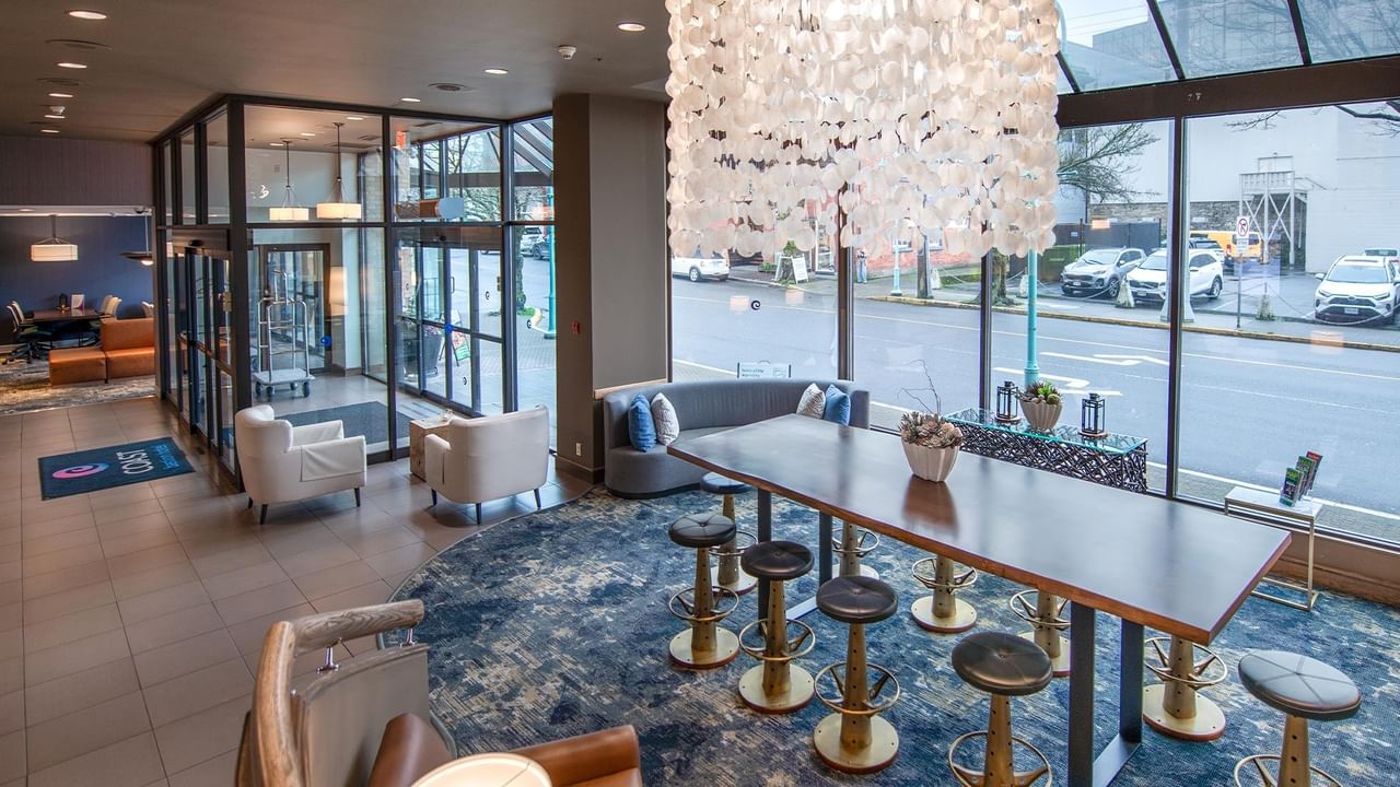 Modern lobby with large chandelier and communal table at Coast Bastion Hotel.