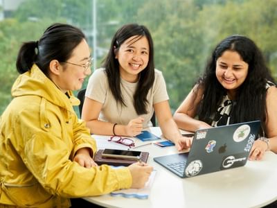 Three residents working together at a table with a laptop on it, at Student Living on Villiers.