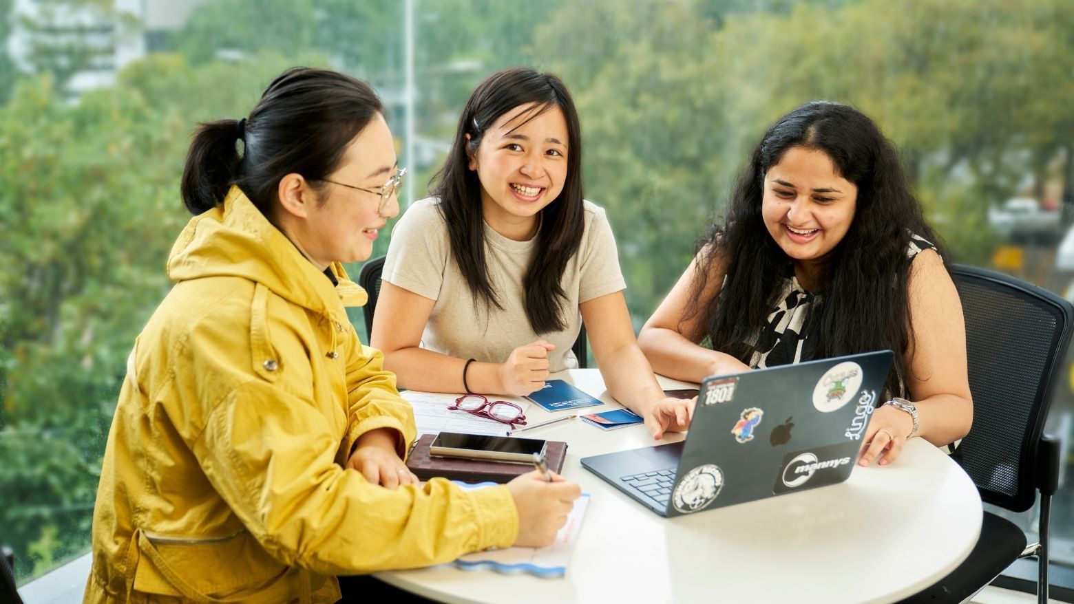 Three residents working together at a table with a laptop on it, at Student Living on Villiers.