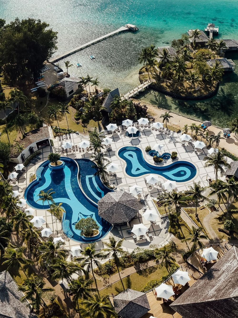 Aerial view of a luxury resort with winding blue swimming pools and tropical palm trees at warwick le lagon-vanuatu