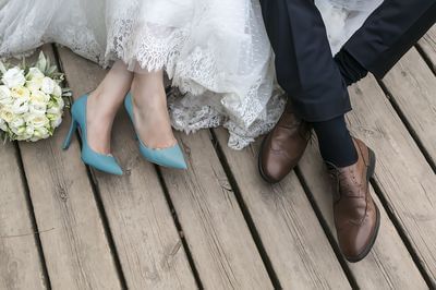 Close-up of the bride and groom's legs by a bouquet on a wooden deck at The J House Greenwich