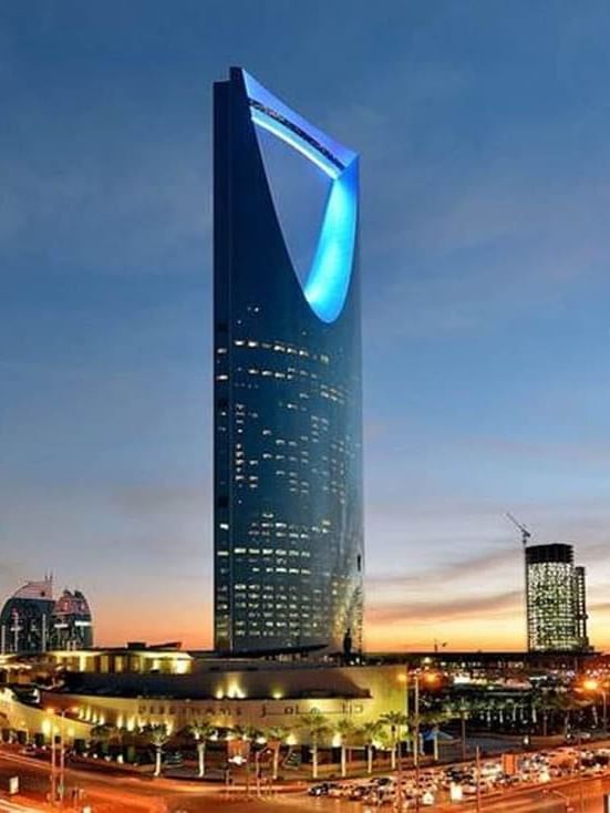 Kingdom Centre tower with a blue lit opening by the city skyline at dusk near Cantonal Hotel by Warwick Riyadh