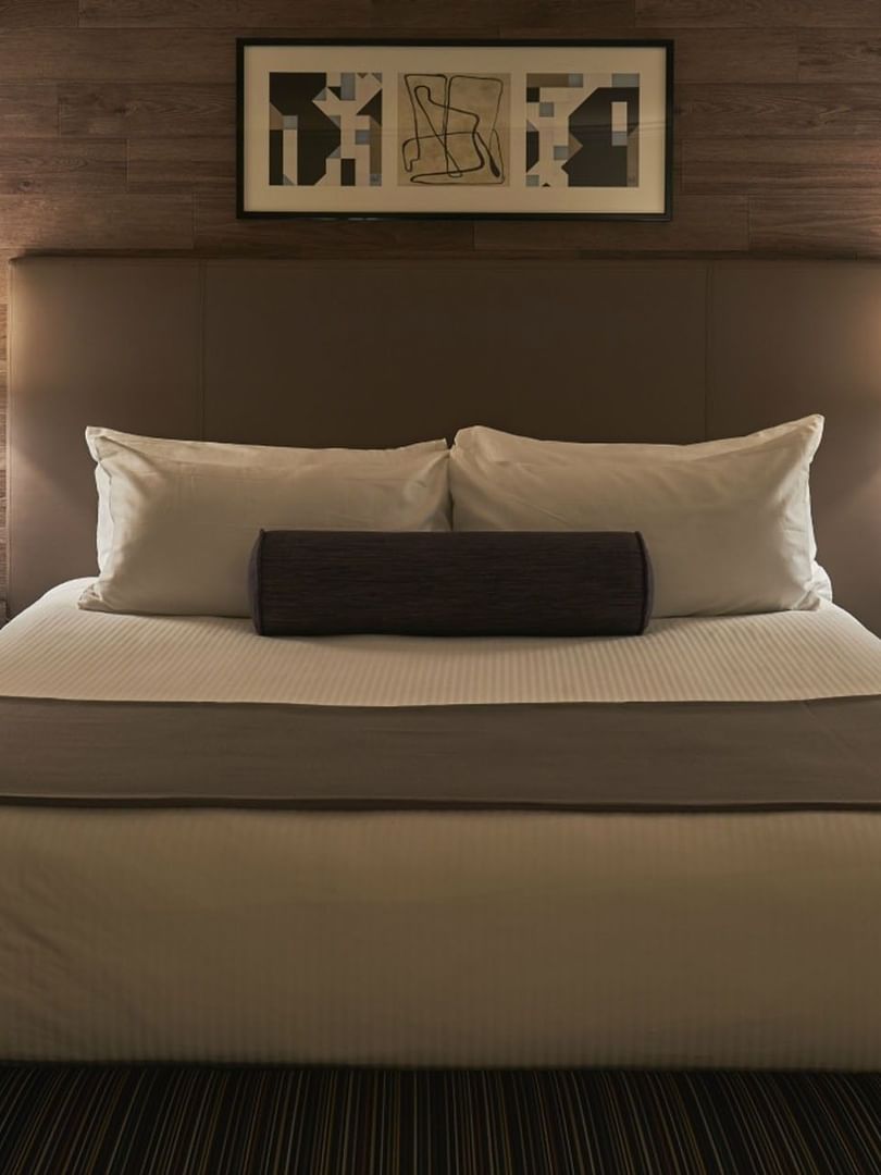 King bed with a purple bolster by white tiered lamps under a wood-paneled wall at Warwick Denver