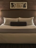 King bed with a purple bolster by white tiered lamps under a wood-paneled wall at Warwick Denver