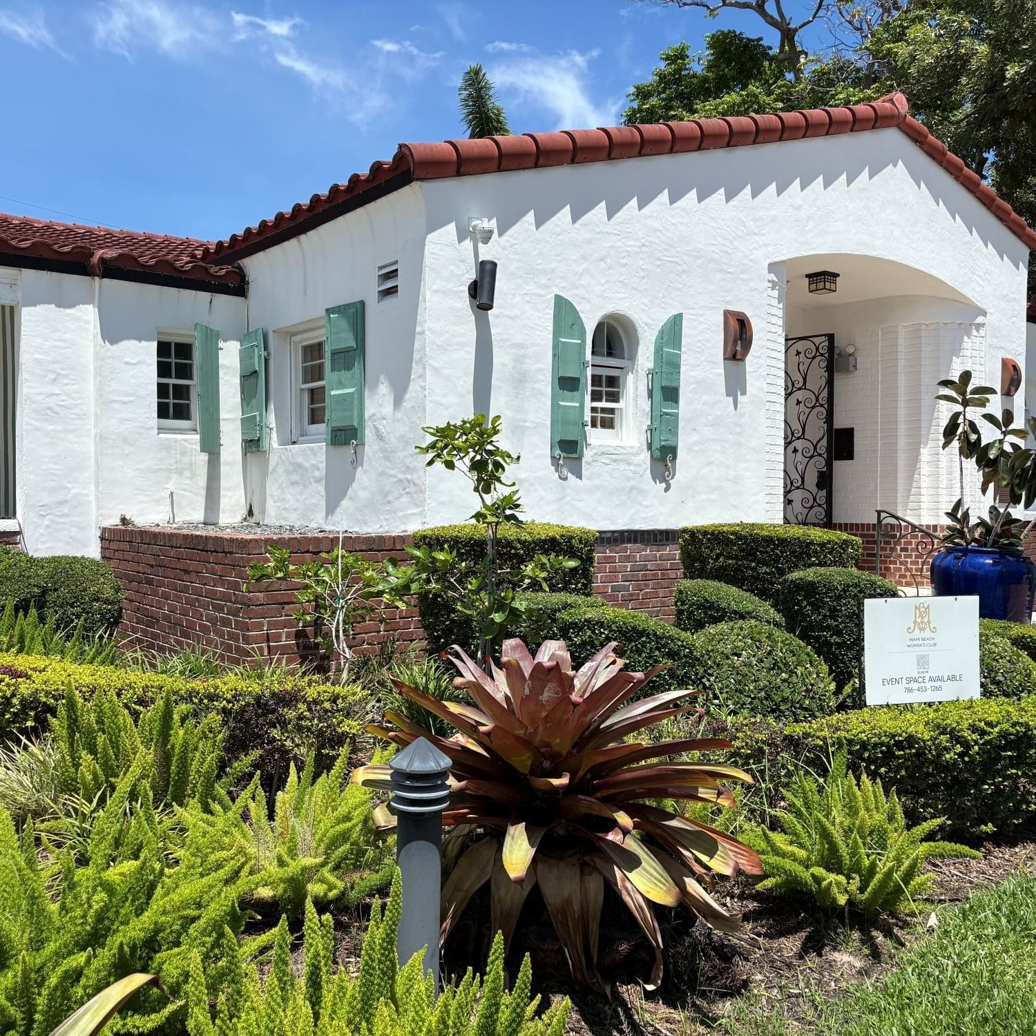 Spanish Colonial architecture of the Tradewinds Apartment Hotel building with a red tile roof and blue decorative planters