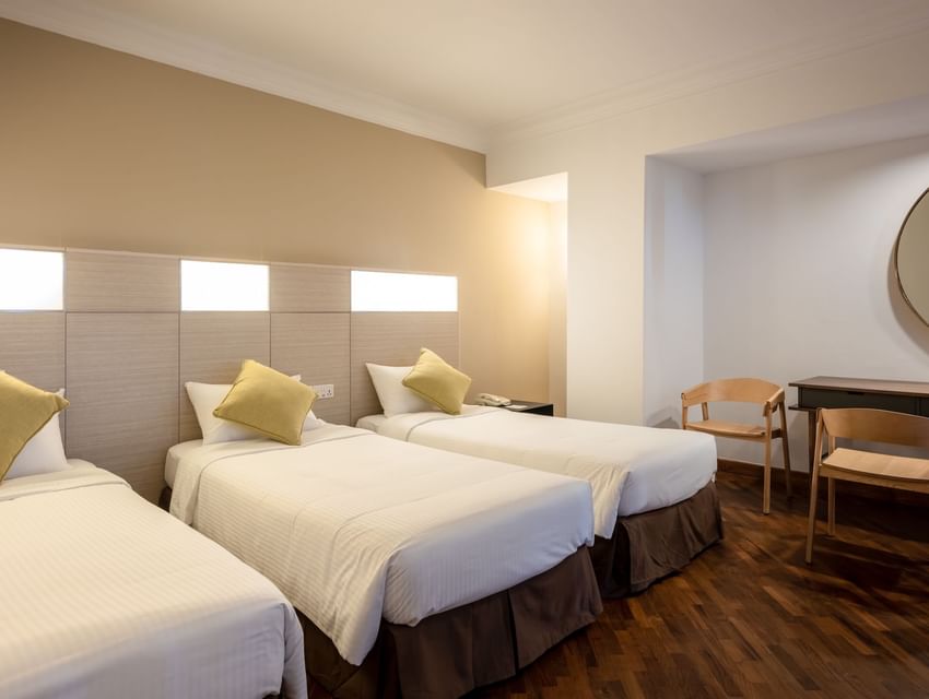 Workspace by the cozy beds in the Family Triple Room with polished hardwood floors at YWCA Fort Canning
