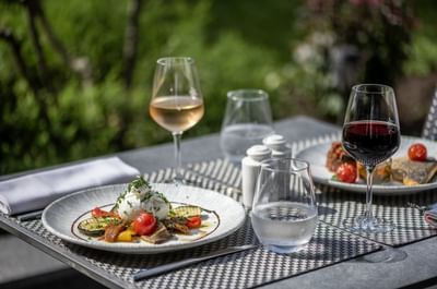 Dining scene with plates of food, featuring burrata cheese & vegetables in Le Lounge Restaurant at Warwick Reine Astrid