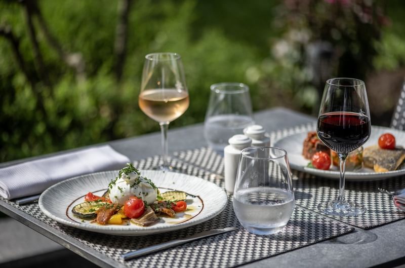 Dining scene with plates of food, featuring burrata cheese & vegetables in Le Lounge Restaurant at Warwick Reine Astrid