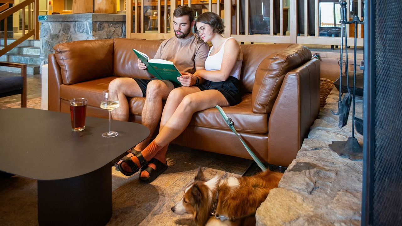 Couple sitting on a couch next to a fireplace with their pet