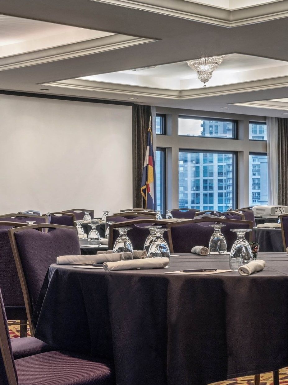 Round tables by purple chairs under crystal chandeliers in Millennium at Warwick Denver