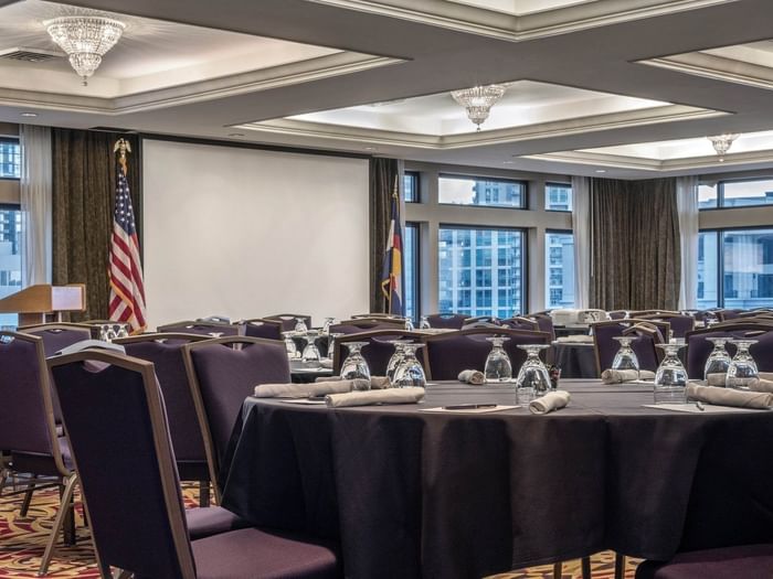 Round tables by purple chairs under crystal chandeliers in Millennium at Warwick Denver