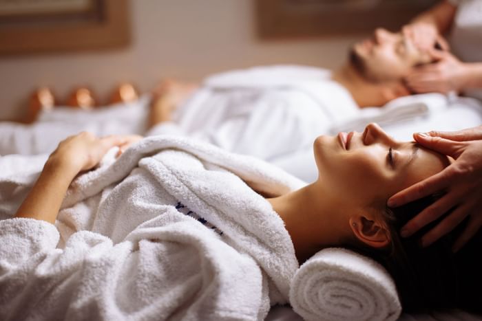 Couples relaxing in white robes by massage tables under the care of a spa therapist at Oregon Garden Resort