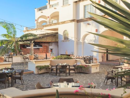 Tahona courtyard with stone flooring, empty dining tables, and a poolside bar at Hacienda del Mar Los Cabos.